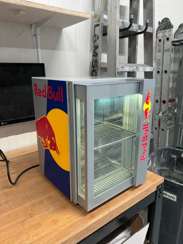 Mini nevera abierta con los estantes iluminados sobre un banco de trabajo